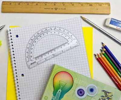   Ruler, pens, pencils and eraser on desk spread out. 