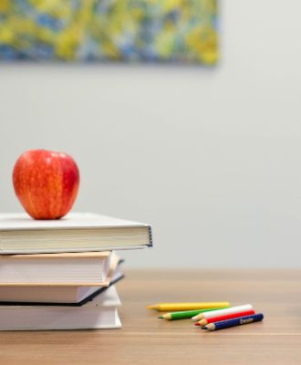  apple on desk with books and pencils around it